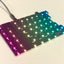 Left half of a bare Sinc PCB plugged in with a columnar gradient from pink to blue on the per-key LEDs.