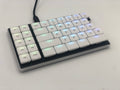Left half of a Cepstrum keyboard with white keycaps. The colors of the per-key LEDs shine through the top middle of each key.