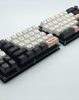 Fully built Quefrency keyboard with one rotary encoder in the outer corner of each half and black, white, and pink keycaps.