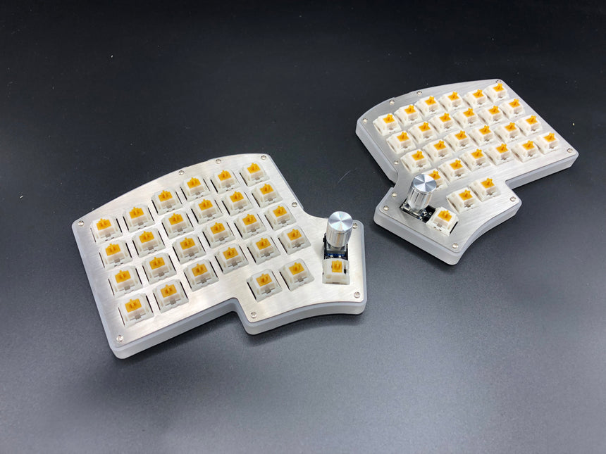Iris keyboard with shiny stainless steel plates and rotary encoders replacing the upper thumb key on each half.