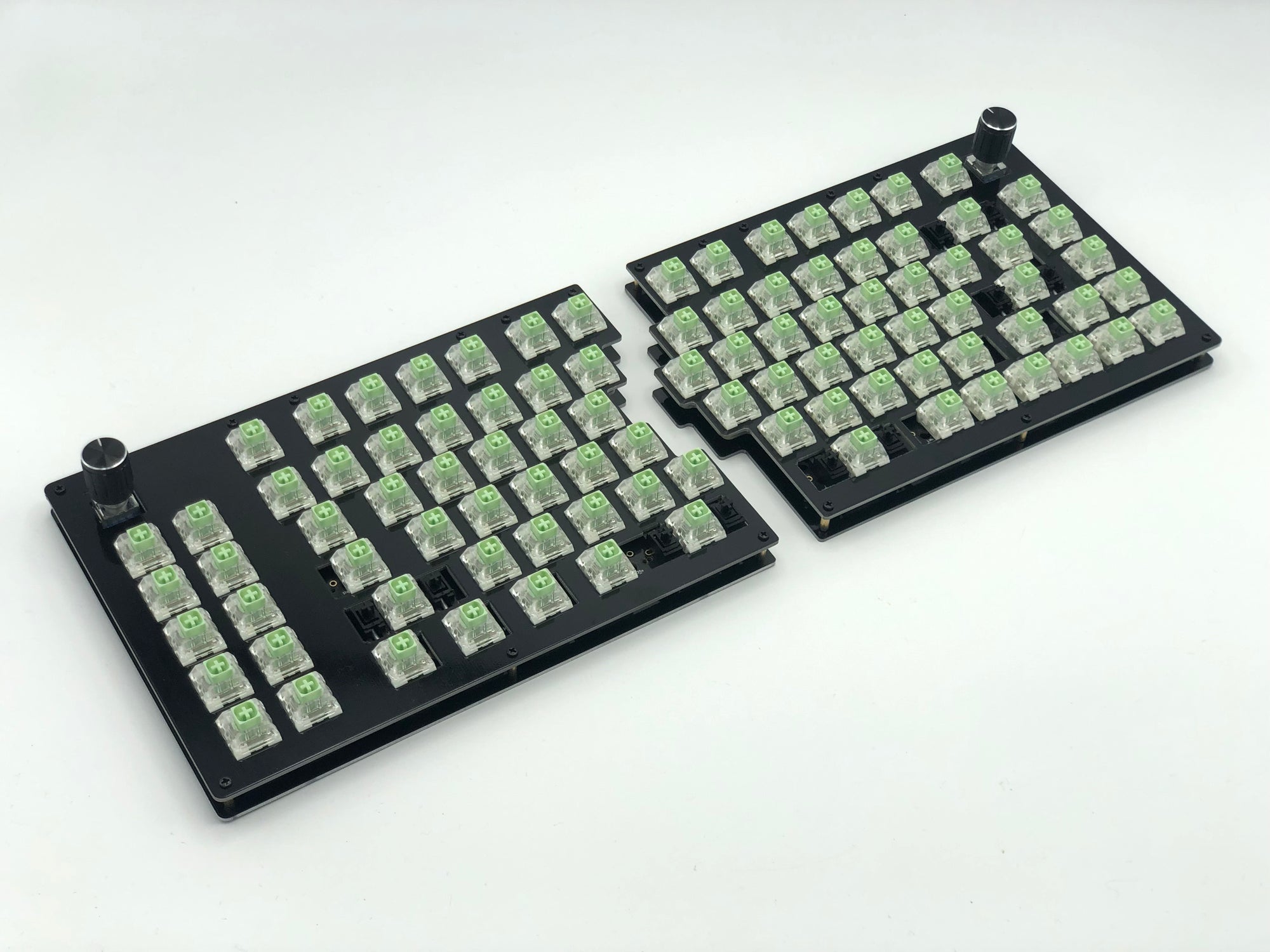 Sinc keyboard with Box Jade switches and a rotary encoder in the outer corners of each half and no keycaps.